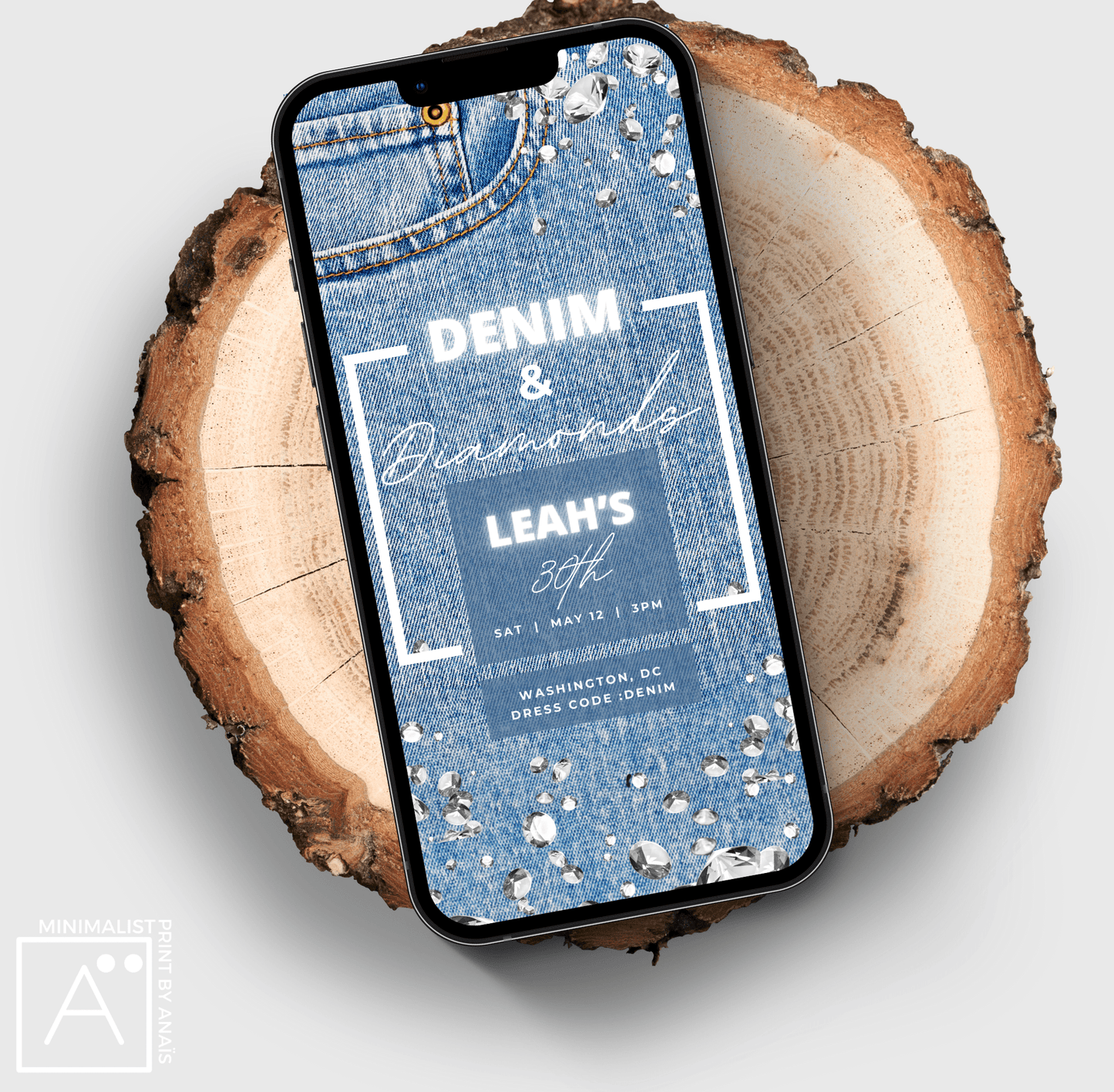 Denim and Diamonds birthday invitation evite displayed on a smartphone, laid on a natural wood slice, showcasing a blue denim texture with sparkling diamond details and white neon text