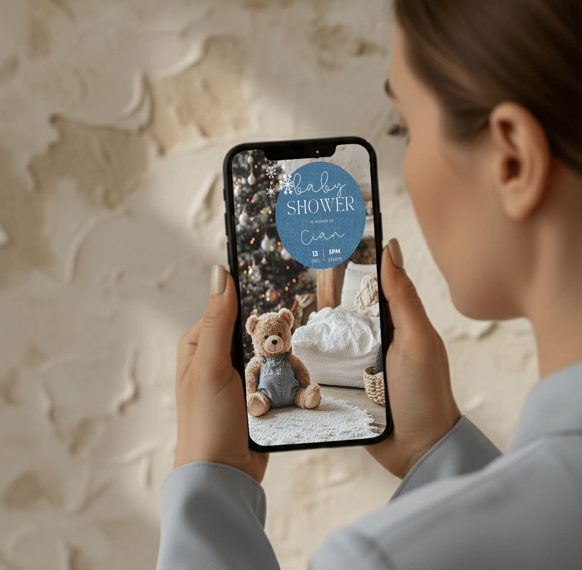 Canva editable baby shower invitation shown on smartphone, denim and teddy design for winter or Christmas baby shower.